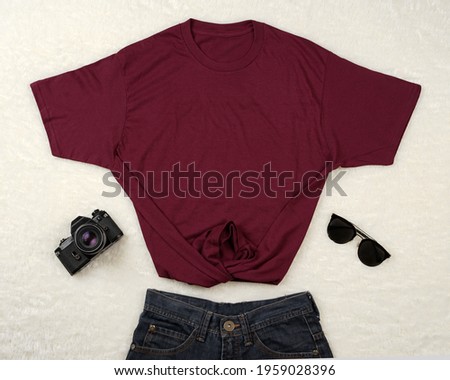 Plain maroon t-shirt and black jeans isolated on white feathers. T-shirts made of cotton are very comfortable for everyday wear. Blank space for your ad. T-shirt mockup.