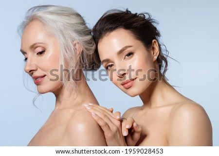 Two smiling women of different ages looking at different side holding hand closeup portrait. Young girl cuddling snuggling mom from back. Warmth in relation between parent and adult kid Royalty-Free Stock Photo #1959028453