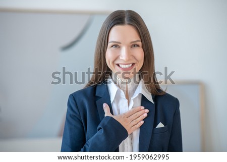 Picture of a young woman putting hand on her heart and smiling