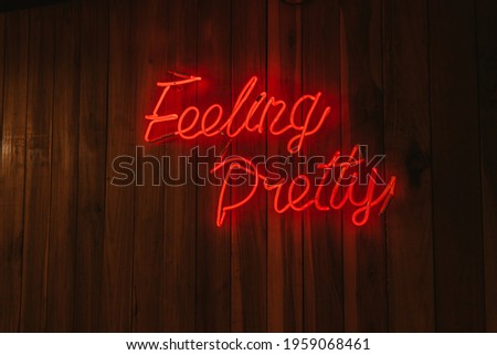 Wide shot of feeling pretty neon sign in red