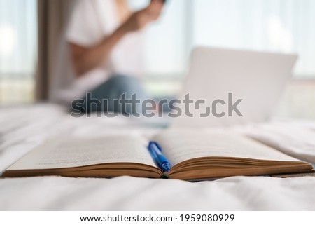 An open book with a pen and a close-up. In the background, a blurry silhouette of a woman. Concept of education.