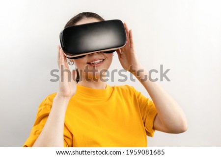 Virtual Reality concept. Portrait of a young smiling woman in virtual reality glasses. White background.