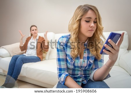 Teenage daughter looking messages in a smartphone and ignoring her furious mother. Bad family communication concept by new technologies Royalty-Free Stock Photo #195908606