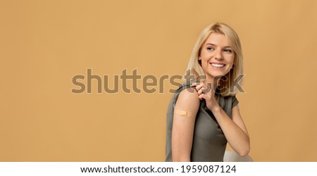 Vaccination saves lives. Happy woman getting vaccinated immunity to covid-19, posing over beige background with empty space, panorama. Female patient showing shoulder with band aid after shot