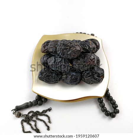 Ajwa dates are round in shape with a smooth but wrinkled skin texture. The flesh of the fruit is a bit sweet like raisins. the photo uses a white background
