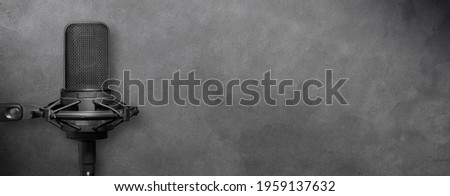 Studio microphone isolated on dark gray concrete background, urban music production or podcast banner with copy space for website design.