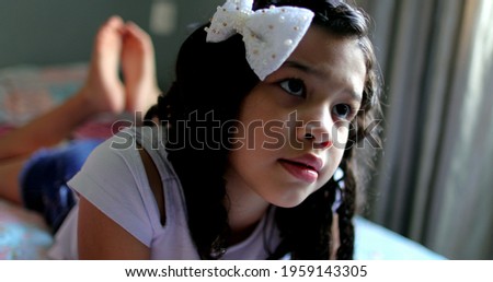 Little girl watching TV lying in bed