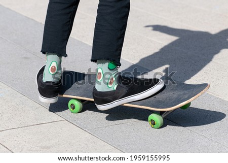 legs of teenager in green socks on a skateboard