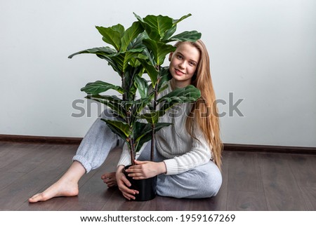 Blonde girl holding home plant. Make your house green