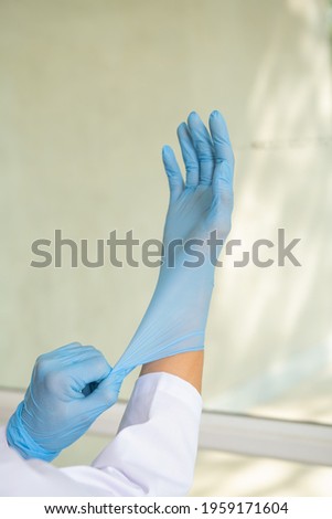 Doctor or nurse putting on blue nitrile surgical gloves, professional medical safety and hygiene for surgery. Coronavirus Vaccine concept. Concept of fight against coronavirus.