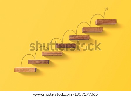 Step by step to grow your business, business success or career path success concept. Wooden blocks arranged in a shape of staircase on yellow background. Royalty-Free Stock Photo #1959179065