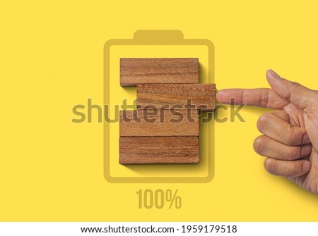 Fully charged, recharge, reboot, refresh or mindset concept. Hand putting wooden blocks with the battery charger and 100% icon on yellow background. Royalty-Free Stock Photo #1959179518