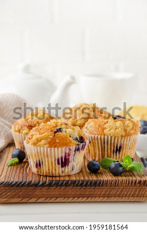 Lemon muffins with blueberries and shtreisel with fresh berries on a white wooden background. Delicious breakfast. Copy space