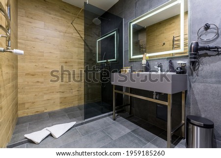 Interior of a large bathroom with black marble tiles and wood-colored tiles, shower and toilet with bidet