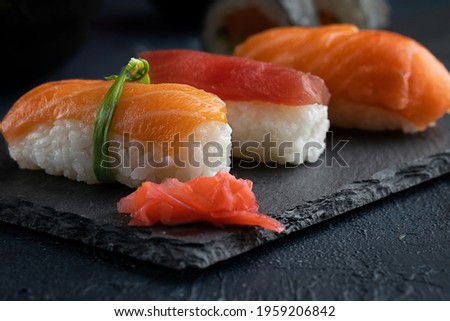Rainbow Sushi nigiri with salmon, tuna and vegetables placed on black rock.Japan restaurant menu.Close up.