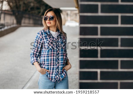 Fashion portrait of beautiful woman with beautiful face, wearing grunge plaid shirt. Posing alone.