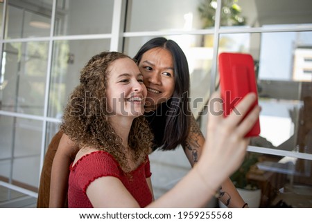 Girlfriends. Pretty multiracial female friends taking selfie with smartphone Lifestyle selfie portrait of two young positive woman taking a self photo