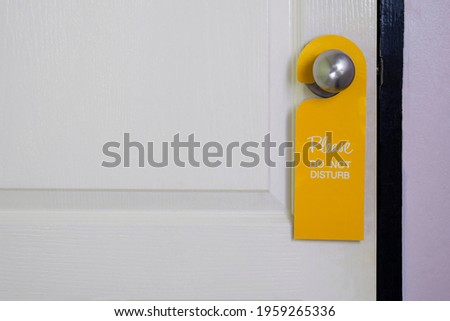 Please do not disturb sign hanging on door handle of white wooden door