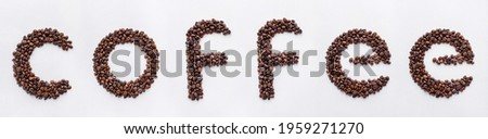 Coffee beans arranged in letters. Coffee sign made of dark roasted coffee beans on white paper background with elegant texture