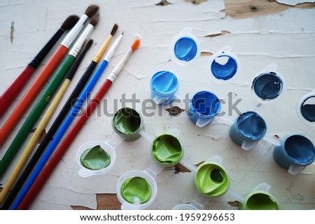 Paints in jars with lids. Drawing pictures by paint numbers. Artist's desktop, paints, brushes