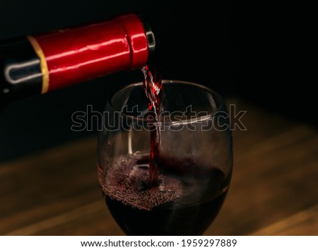 wine bottle filling a glass on a black background