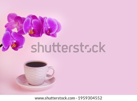 Pink orchid and cup of coffee on the pink background. Breakfast on Mother's day or Women's day. Close-up. Copy space.