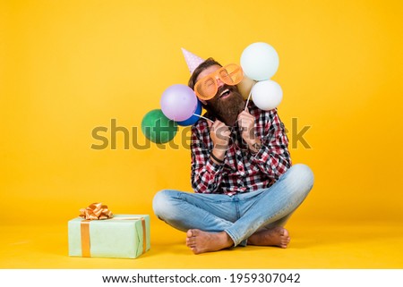so good. bearded man feel the joy. man with gift box celebrating birthday. mature hipster with bright colorful balloons. Crazy funny guy. Relaxed happy birthday guy looks cheerful