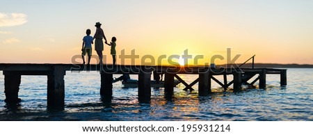 Family silhouettes on a bridge during sunset