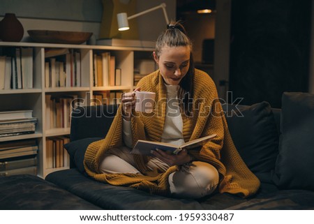 woman reading book and drinking coffee or tea at home Royalty-Free Stock Photo #1959330487