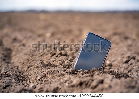 the phone sticks out of the ground in the field.