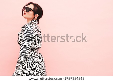 High fashion portrait of young beautiful brunette woman wearing nice trendy summer zebra coat.Sexy fashion model posing near pink wall in studio.Fashionable female in sunglasses Royalty-Free Stock Photo #1959354565