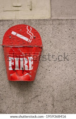 a red ashtray with the inscription 'fire' is mounted on a wall