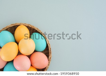 Minimalistic Easter background with delicate Easter eggs in pastel colors on a blue background. Easter composition. Easter tradition of painting eggs. Top view, flat lay, copy space