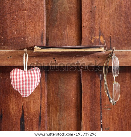 Fabric heart on the wall with old notebook and old glasses