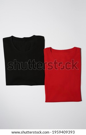 Two folded colorful black and red cotton t shirts isolated on white background. Flat lay tees template. Clothes, fashion, retail concept. Vertical shot Royalty-Free Stock Photo #1959409393