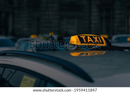 A close-up shot of a taxi sign in the warm colours of sunset with bokeh lights in the background  Urban transportation 
