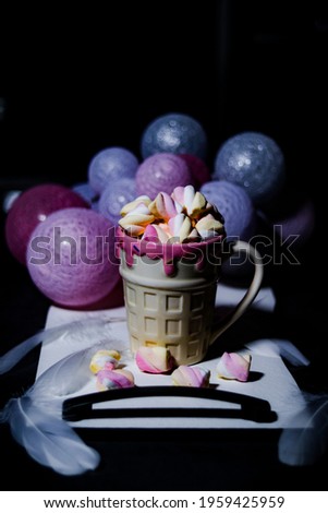 a cup of coffee on a tray with pink balls in the background, a picture of where you taste