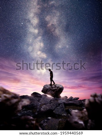 A man standing on A rock as the milky way galaxy rises into the night sky at dusk. Photo composite