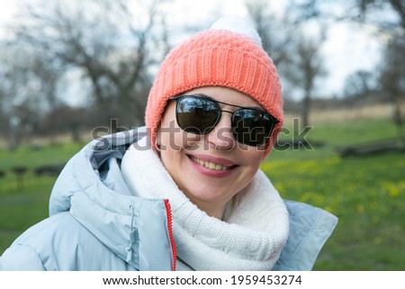 A middle-aged woman enjoys the fresh air in early spring in the forest. The woman is dressed in a sporty style.