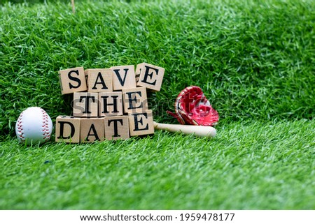 Baseball with Save the Date with bat are on green grass