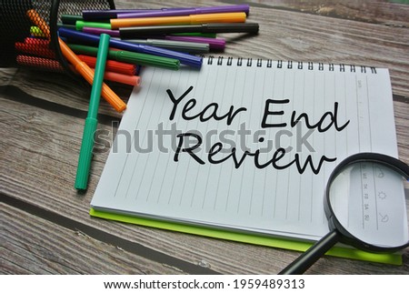 Selective focus of magnifying glasses, colorful marker pen and notebook written with YEAR END REVIEW. Business, financial, industrial concept.