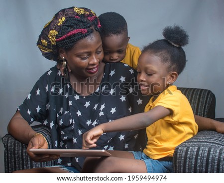 
Happy family consisting of a mother and her boy and girl children sitting happily together and playing with a big smart phone or phone tab on a sofa chair with phone in their hands 