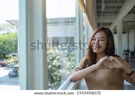 A beautiful asian woman making heart hand sign with feeling happy