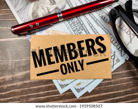 Business concept.Text MEMBERS ONLY with pen,glasses and banknote on brown wooden background.