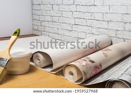 Multicolored patterned wallpaper, brush, glue are prepared for home interior renovation. Home renovation concept. Royalty-Free Stock Photo #1959527968