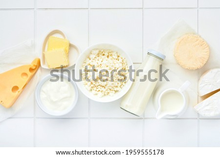 Glass of milk, cottage cheese, ricotta, sour cream, cheese, camembert and butter on white table background. Different dairy products. Milk concept. Top view with copy space. Mock up.
