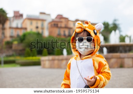 A cute Asian girl wearing a giraffe costume, Sunglasses travel in a new normal state with a face mask.