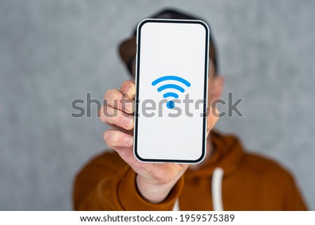 Man hand holding silver smartphone isolated on light background. Phone mockup with white screen and wi-fi icon