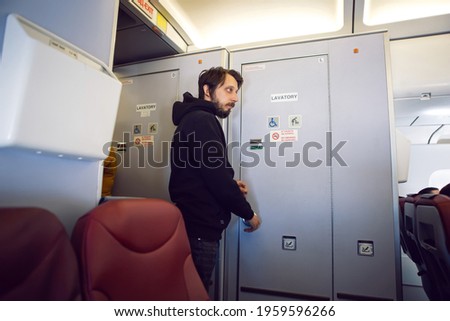 man in black clothes goes to the toilet on the plane