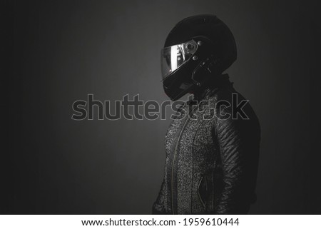 Motorbiker is looking aside on a dark background with a copy space. Side view. Royalty-Free Stock Photo #1959610444